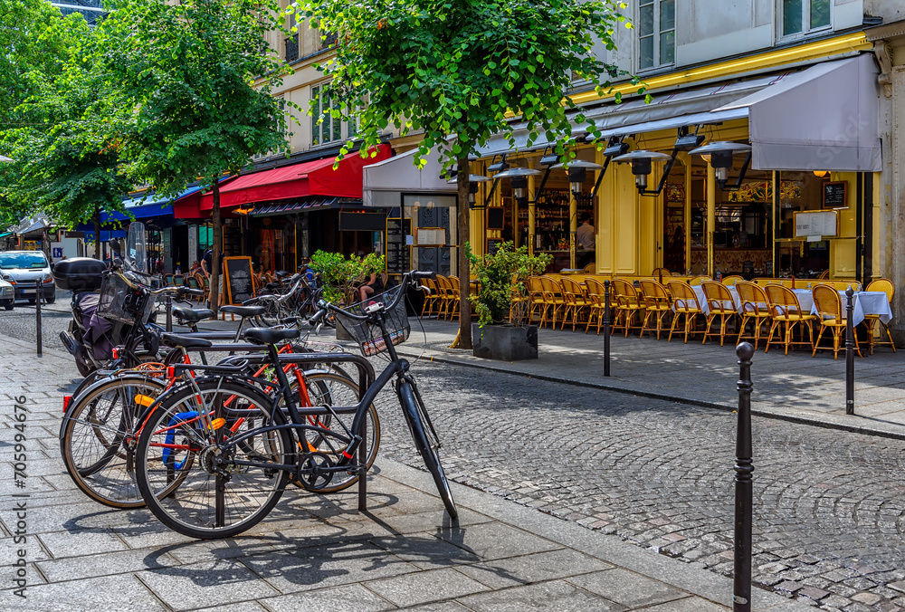 Fototapeta premium Typical view of the Parisian street with tables with tables of cafe in Paris, France. Architecture and landmark of Paris. Cozy Paris cityscape