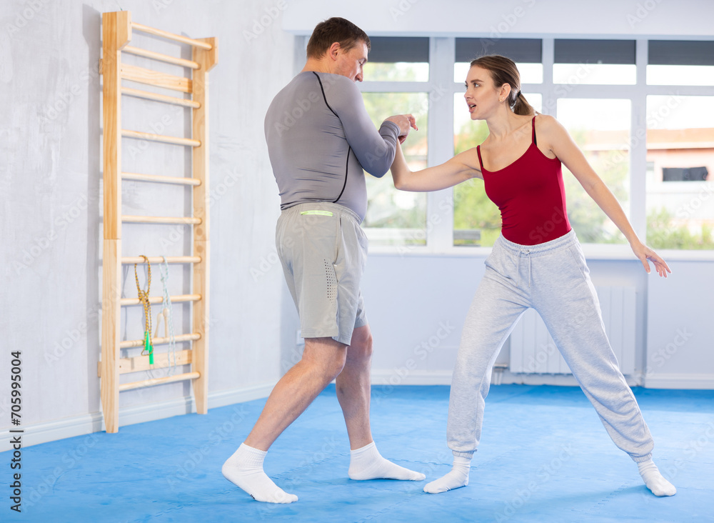Obraz premium Adult man and young woman training self-defense techniques in studio