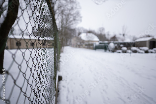 Siatka ogrodzeniowa uciekająca wzdłuż kadru w nieostrość w pochmurny zimowy dzień w zachodniej Polsce