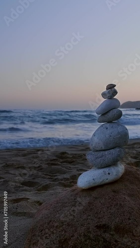 Balance stones stack on beach at sunset. Rock and sea waves in background. photo
