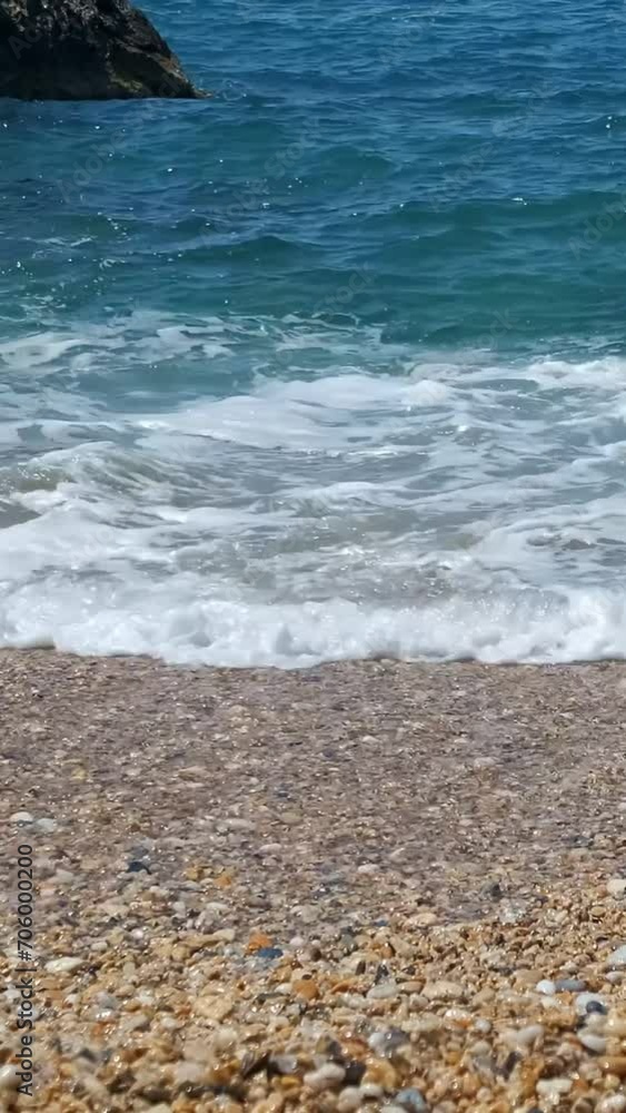 Close-up of clear blue tidal waves splash and spray on yellow pebbles on sunny summer day, Greece Close-up of clear blue tidal waves splash and spray on yellow pebbles on sunny summer day, Greece