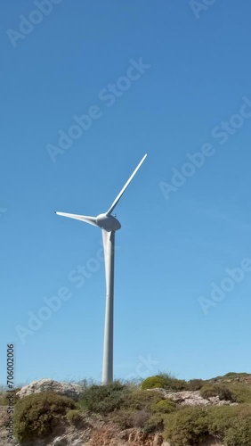 Wind turbine rotating and generating electricity in summer landscape on sunny day photo