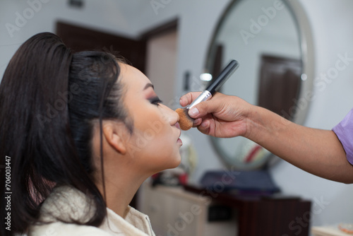 Photo of a woman being made up with a brush in a spa or beauty salon. Concept of women, beauty and self love.