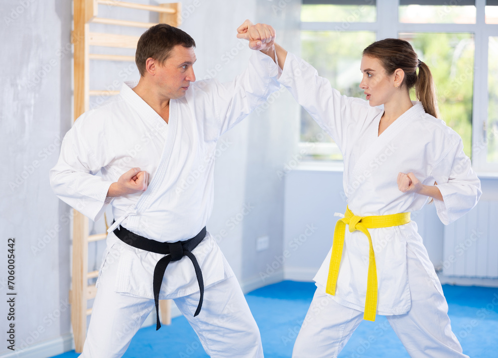 Obraz premium Sparring woman and man in white kimono during karate training in the gym