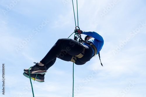 Woman rappeller hanging from the rope doing maneuvers. Healthy and dangerous sport. photo