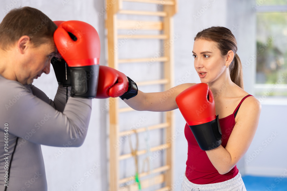 Adult man and young woman train boxing punches in studio