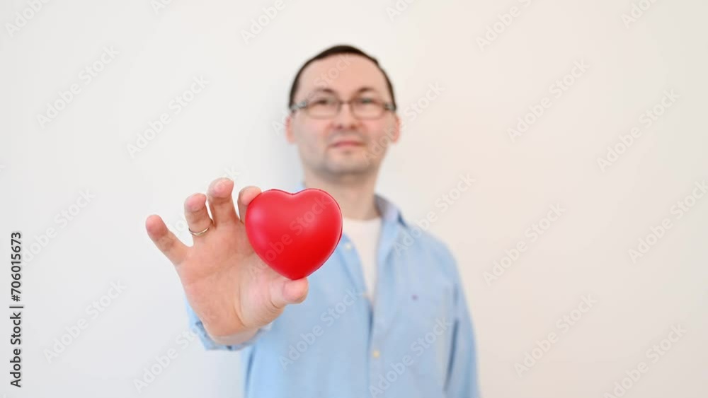 Young smiling man holding heart against white wall. VAlentines footage Young smiling man holding heart against white wall. VAlentines footage