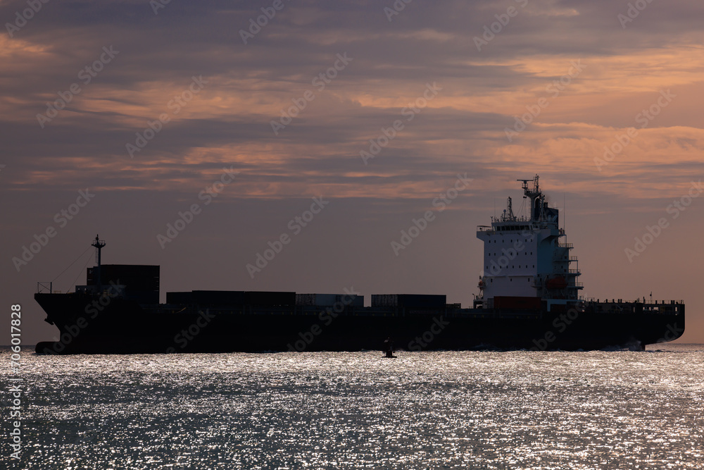 Seascape and silhouette container ship floating in sea
