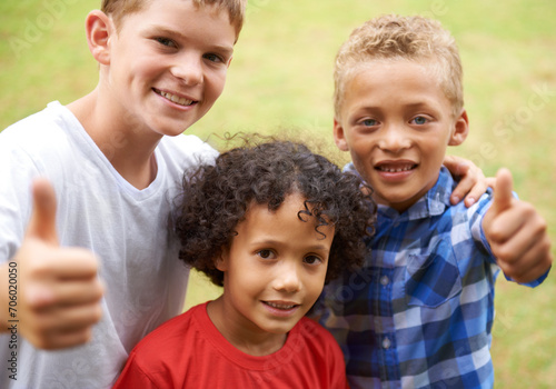 Happy children, portrait and thumbs up for outdoor teamwork, winning or good job together in nature. Group of casual young boys smile and hug with like emoji, yes sign or OK for success at the park