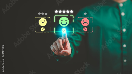 Customer hand touching the virtual screen on happy smile face icon to give satisfaction in service. Concept of assessment testimonial customer service and feedback, Opinion rating very impressed.