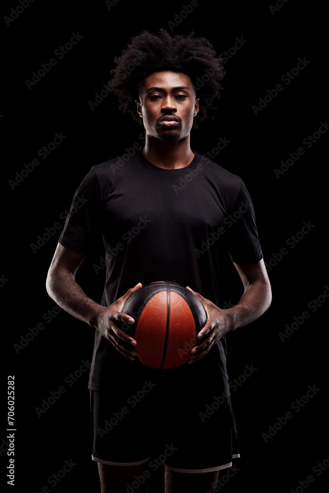 Basketball player holding a ball. Concentrated african american sports man against black background.