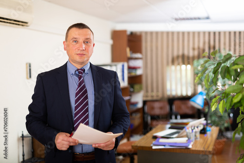 Concentrated businessman standing posing at workplace in office