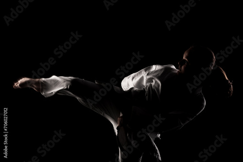 Young girl exercising karate. Child in kimono against black background.