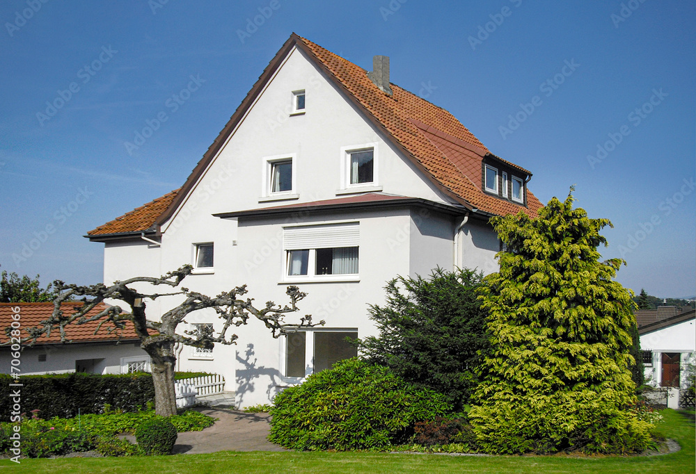 generic old family house in Germany with white facade and garden in front