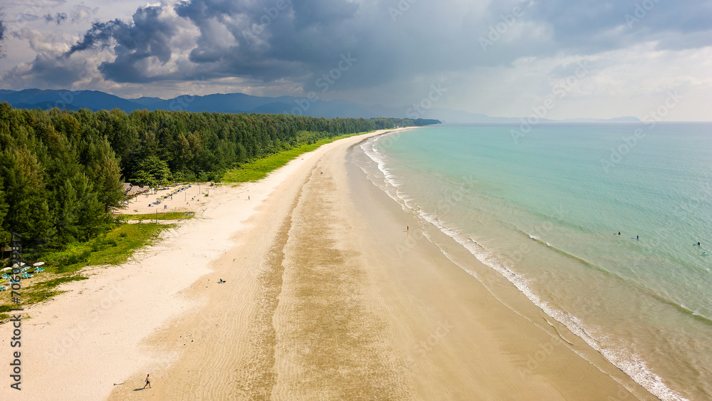 Aerial view of a large, empty tropical beach surrounded by lush foliage
