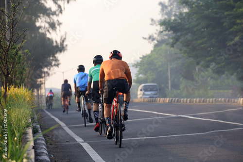 rear view of a group of people cycling in the morning with morning sunlight. cycling to maintain fitness and a healthy lifestyle.