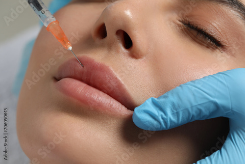 Doctor giving lips injection to young woman in clinic  closeup. Cosmetic surgery