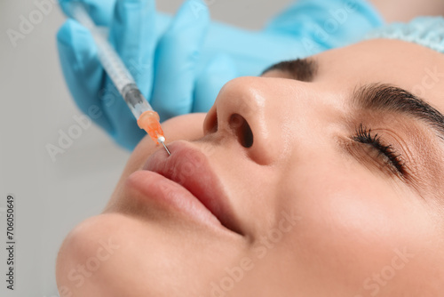 Doctor giving lips injection to young woman in clinic, closeup. Cosmetic surgery