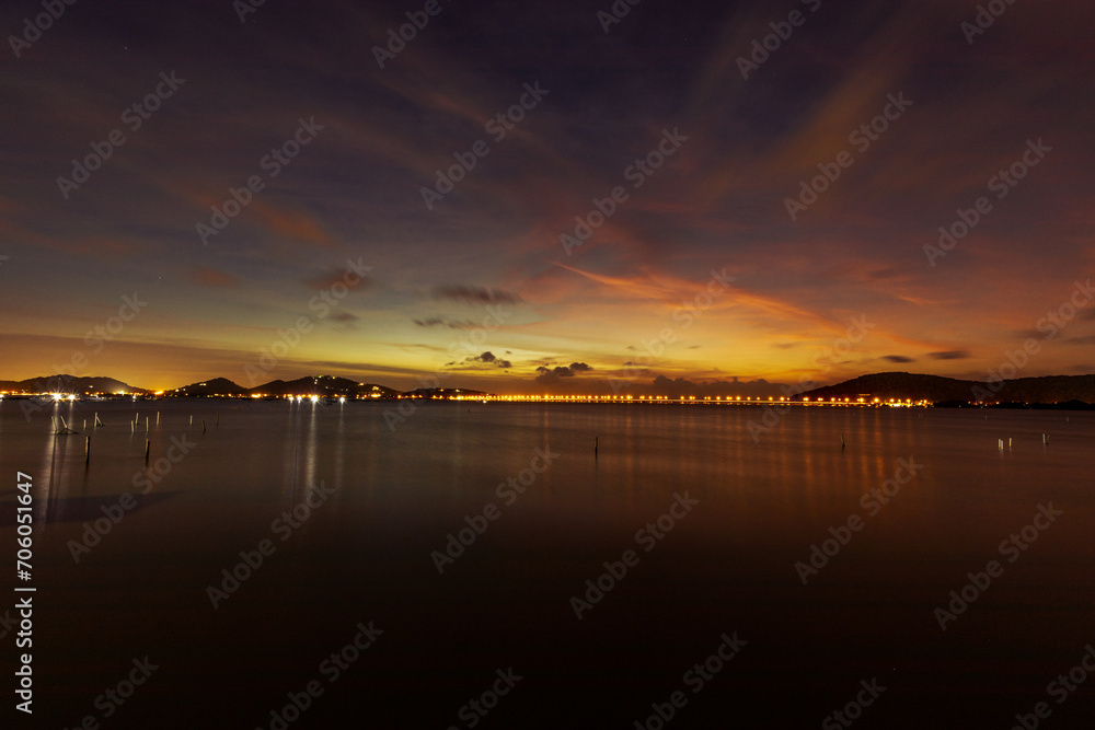 Fototapeta premium The background of the sea by the evening sea, with natural beauty (sea water, rocks, sky) and fishermen are fishing by the river bank, is a pleasure during travel.