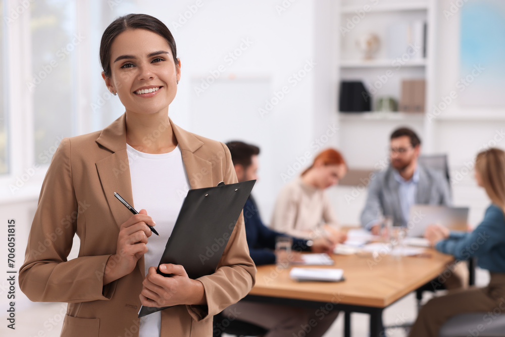Team of employees working together in office. Happy woman with clipboard indoors Team of employees working together in office. Happy woman with clipboard indoors