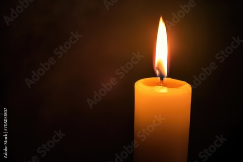 A single white candle burning against a dark backdrop.
