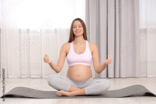 Pregnant woman meditating on yoga mat at home Free Download Pregnant woman meditating on yoga mat at home - GFXLoad