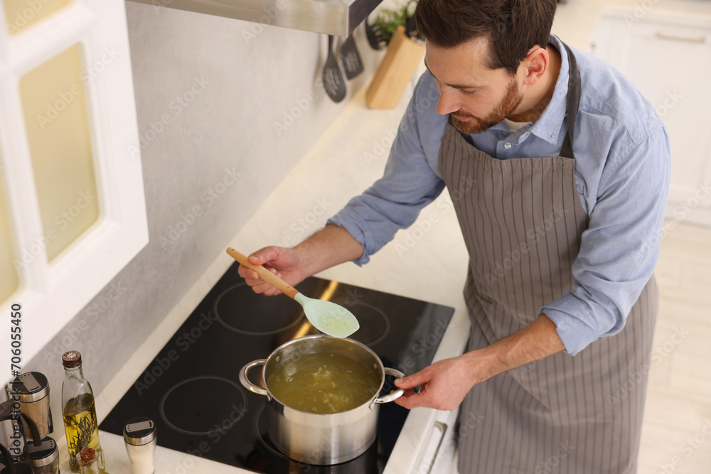 Man cooking delicious chicken soup in kitchen, above view Man cooking delicious chicken soup in kitchen, above view