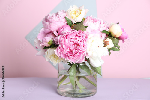 Bouquet of beautiful peonies in vase on lilac table