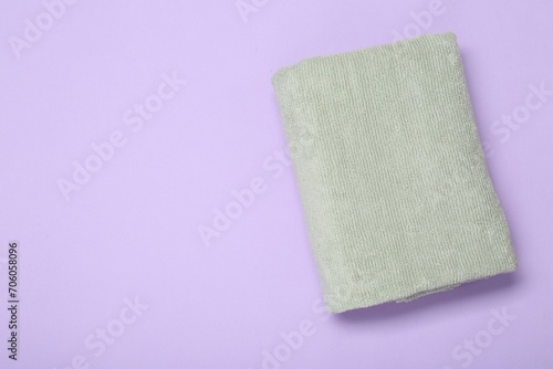 Soft towel on violet background, top view. Space for text