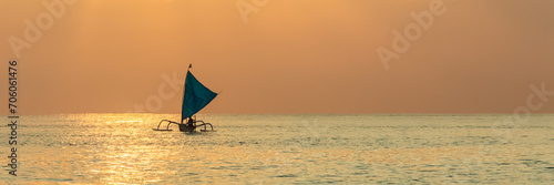 Silhouette of outrigger sailboat at sunset in Bali, Indonesia. photo