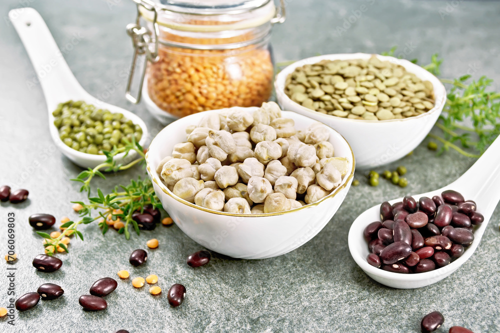 Legumes in bowls and spoons on granite table Legumes in bowls and spoons on granite table