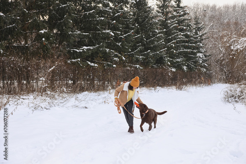 Woman and her dog playing with flying disk in snowy park