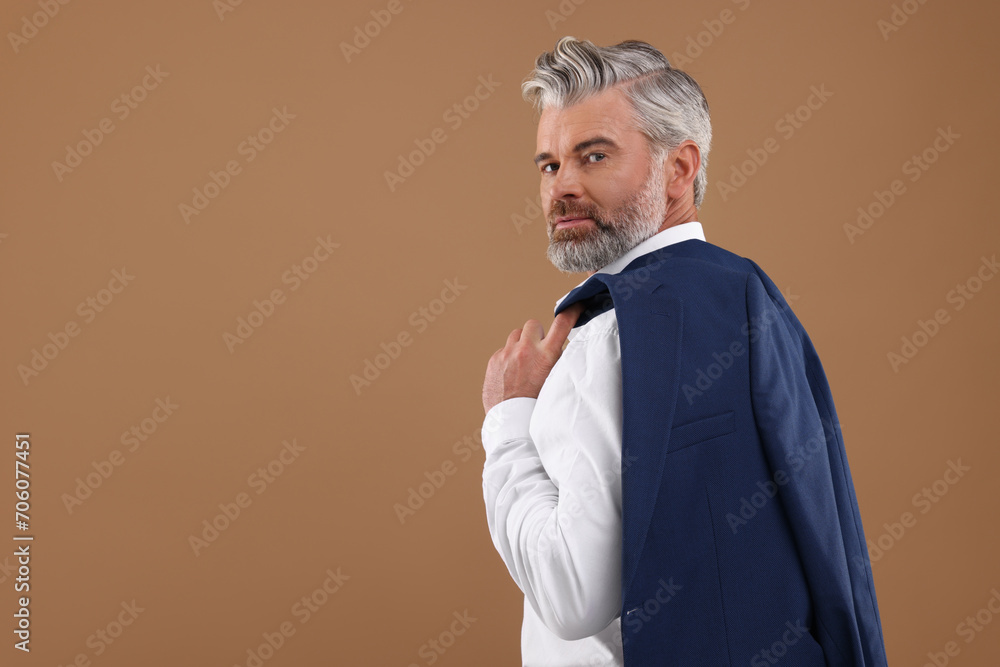 Portrait of confident man with beautiful hairstyle on light brown background. Space for text