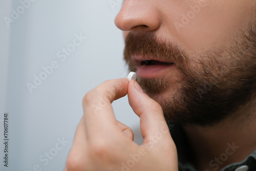 Man taking antidepressant pill on light background, closeup photo