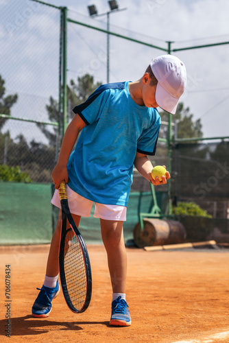 Little boy playing tennis on a dirt court