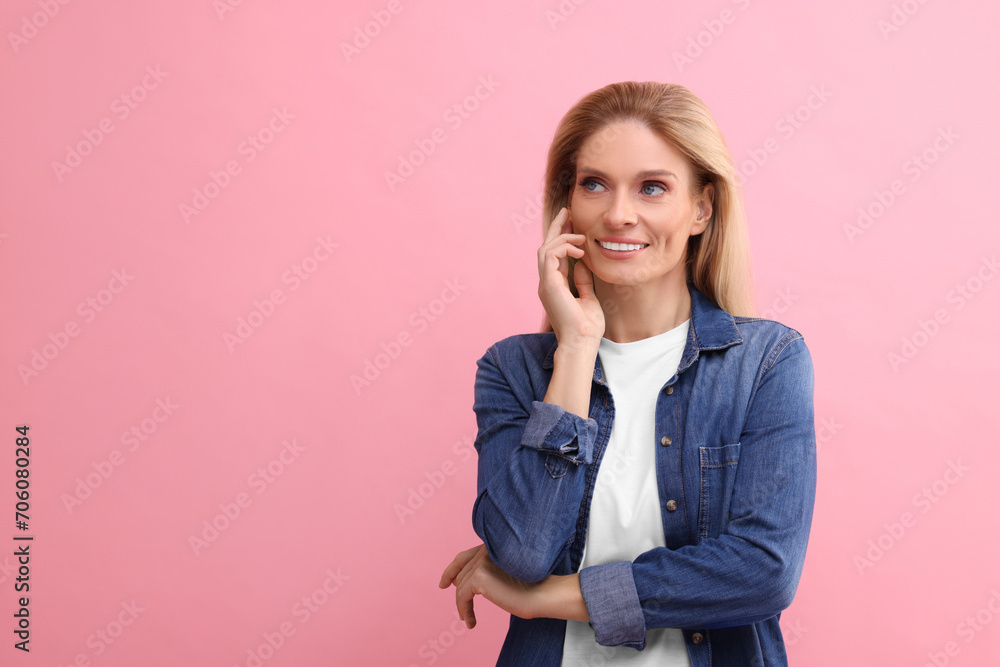 Portrait of smiling middle aged woman with blonde hair on pink background. Space for text Portrait of smiling middle aged woman with blonde hair on pink background. Space for text