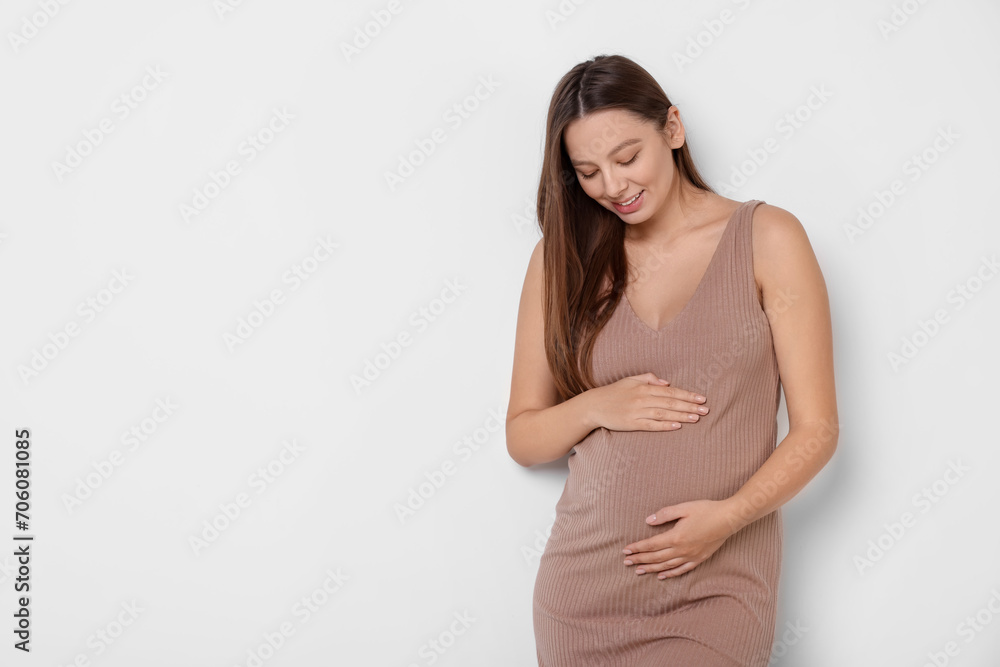 Beautiful pregnant woman in beige dress on white background, space for text