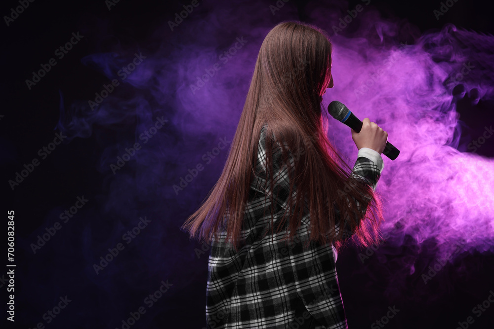 Woman with microphone singing in neon lights, space for text