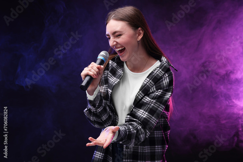 Emotional woman with microphone singing in color lights