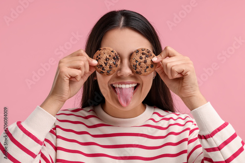 Young woman with chocolate chip cookies on pink background photo
