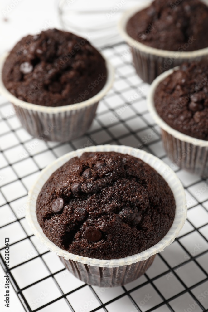 Tasty chocolate muffins and cooling rack on white table, closeup Tasty chocolate muffins and cooling rack on white table, closeup