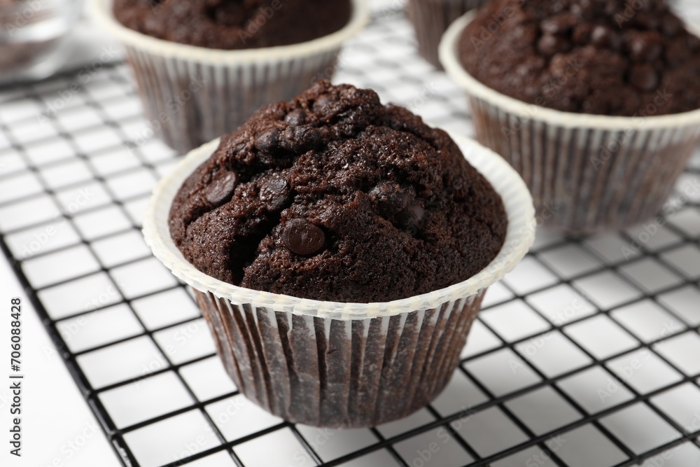 Tasty chocolate muffins and cooling rack on white table, closeup Tasty chocolate muffins and cooling rack on white table, closeup