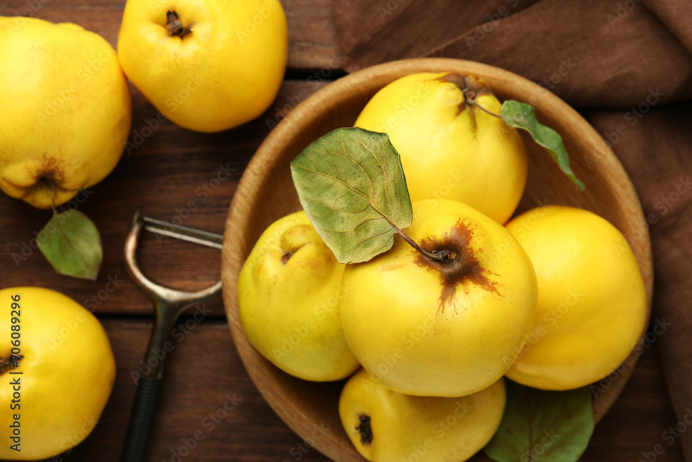 Tasty ripe quince fruits in bowl and peeler on wooden table, flat lay Tasty ripe quince fruits in bowl and peeler on wooden table, flat lay
