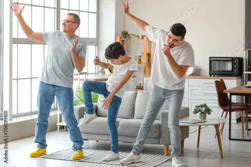 Happy little boy with his dad and grandfather dancing at home photo