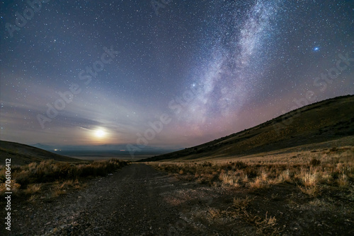 The moon and Milky Way over a grassland landscape photo
