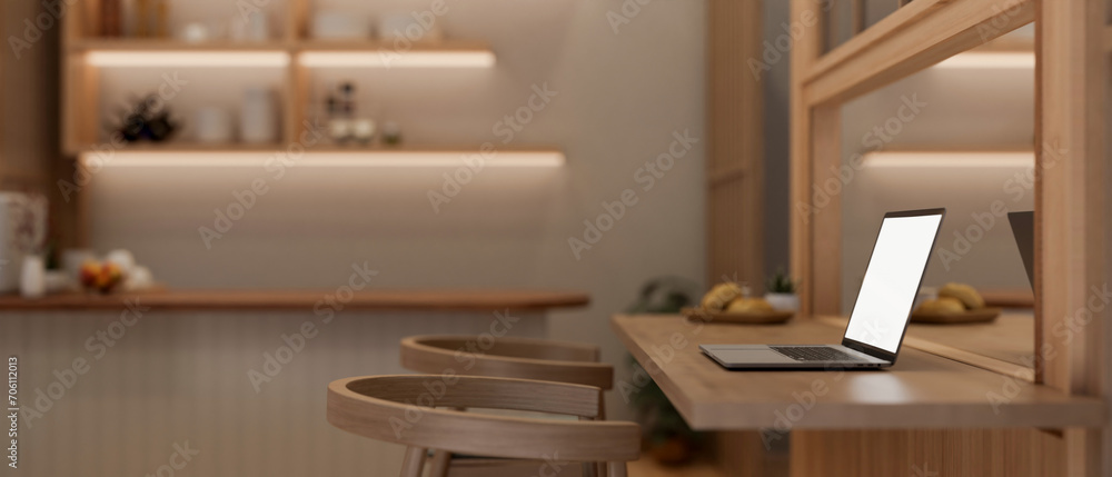 Side view image of a laptop computer on a wooden dining table in a modern, luxury dining room. Side view image of a laptop computer on a wooden dining table in a modern, luxury dining room.