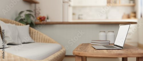 A laptop on a hardwood coffee table in a cosy Scandinavian living room with a cosy wicker couch.