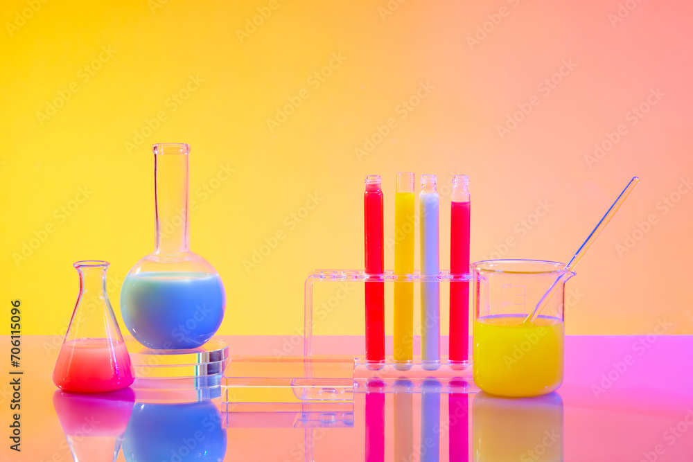 Close up of colorful liquids in test tubes and glass laboratory flasks on a pink yellow gradient background. Empty podium for product display with laboratory space. Close up of colorful liquids in test tubes and glass laboratory flasks on a pink yellow gradient background. Empty podium for product display with laboratory space.