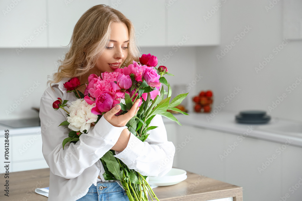 Young woman with peony flowers in kitchen Young woman with peony flowers in kitchen