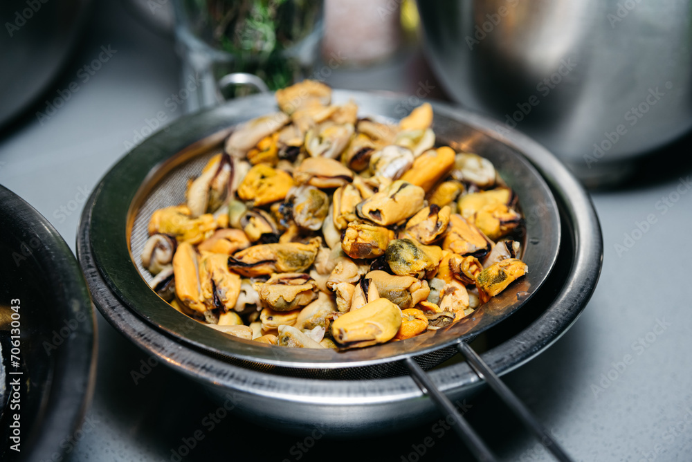 Peeled Mussels Draining in a Sieve. Fresh peeled mussels in a sieve, with their juices being drained over a bowl, capturing a step in seafood preparation. Peeled Mussels Draining in a Sieve. Fresh peeled mussels in a sieve, with their juices being drained over a bowl, capturing a step in seafood preparation.